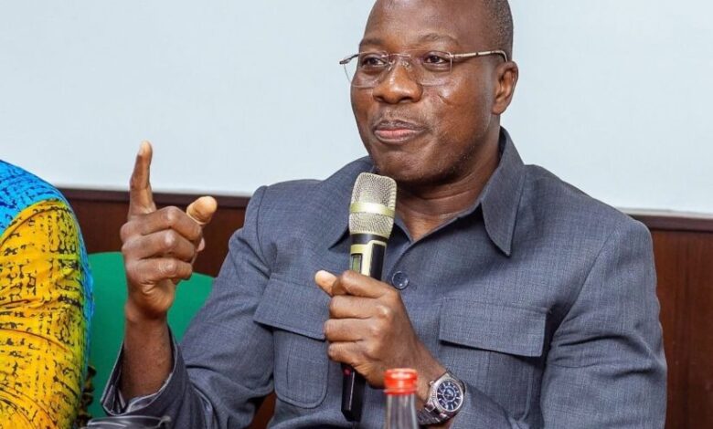 Mahama Ayarega Seated and speaking into a micophone.